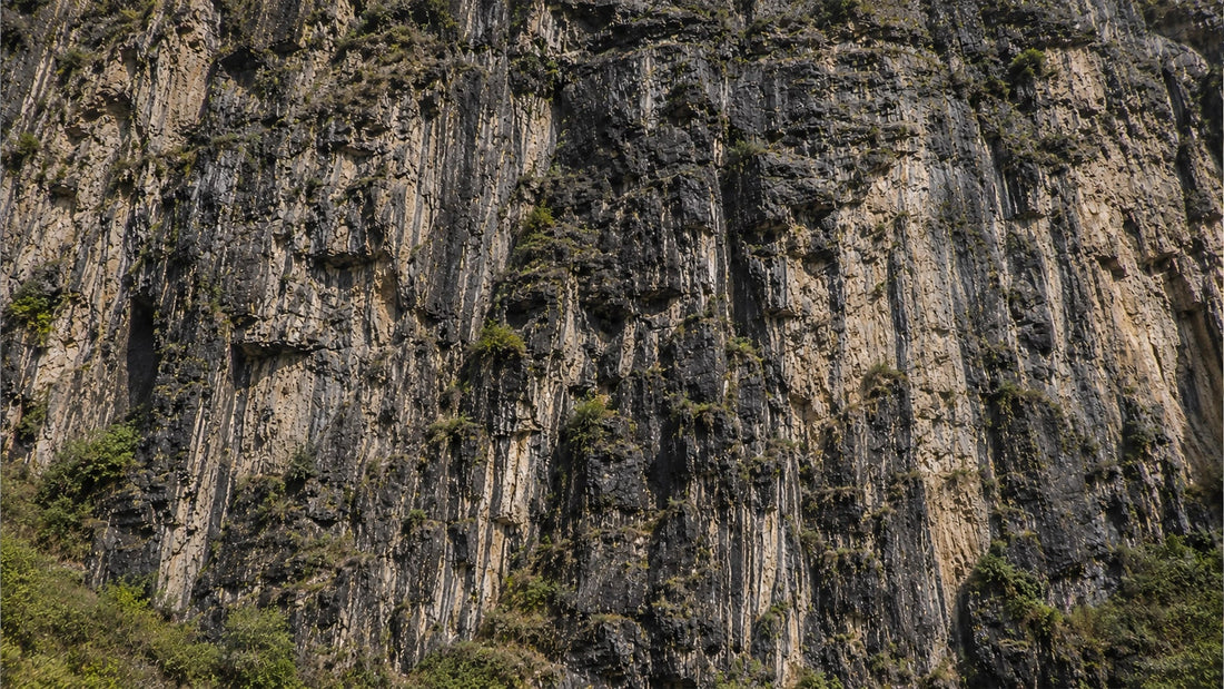 Natural raw shilajit resin emerging from rugged mountain rock formations with dark mineral-rich textures and earthy tones.