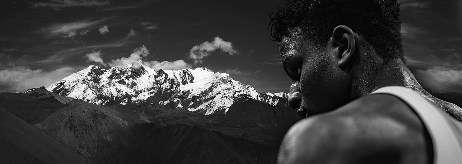 Person gazing at a snow-capped mountain under a dramatic sky