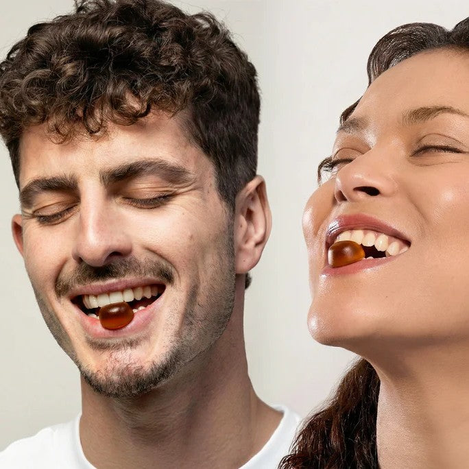 Close-up of a smiling man and woman enjoying softgel wellness supplements, showcasing healthy lifestyles, bright smiles, and a clean, minimalist background.